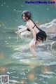 A woman in a black bikini standing in the water.