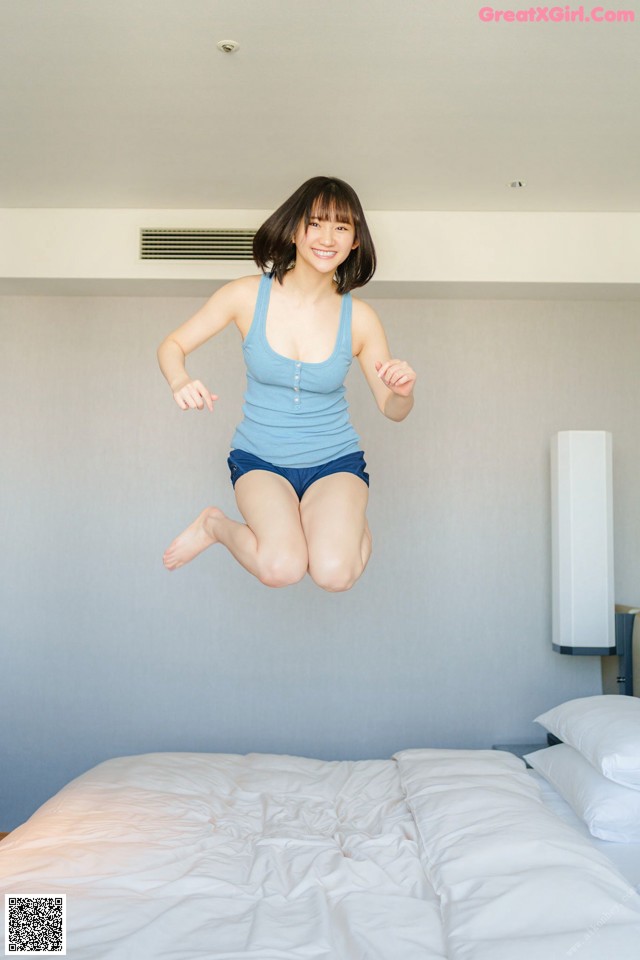 A woman jumping on a bed in a bedroom.
