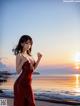 A woman in a red dress standing on a beach.