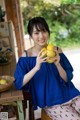 A woman sitting on a stool holding two lemons.