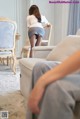 A woman in a skirt and stockings is sitting on a couch.