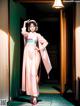 A woman in a pink kimono standing in a hallway.