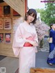 A woman in a pink kimono standing in front of a building.