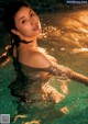 A woman in a swimming pool with water splashing around her.