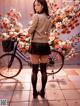 A woman standing next to a bicycle in front of flowers.