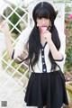 A woman with long black hair holding a pink ice cream cone.