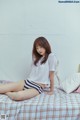 A woman sitting on top of a bed next to a teddy bear.