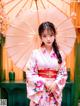 A woman in a pink kimono holding an umbrella.