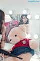 A woman sitting in front of a mirror holding a teddy bear.