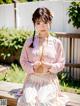 A woman in a pink kimono sitting on a wooden bench.